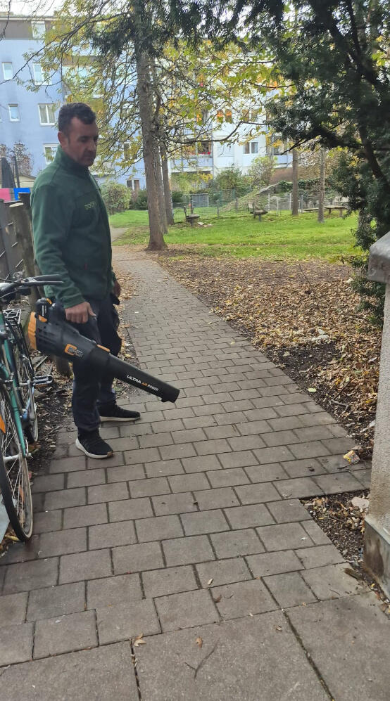 Mitarbeiter von DOCE'S Hausmeisterdienst bei der Laubentfernung mit einem Laubbläser